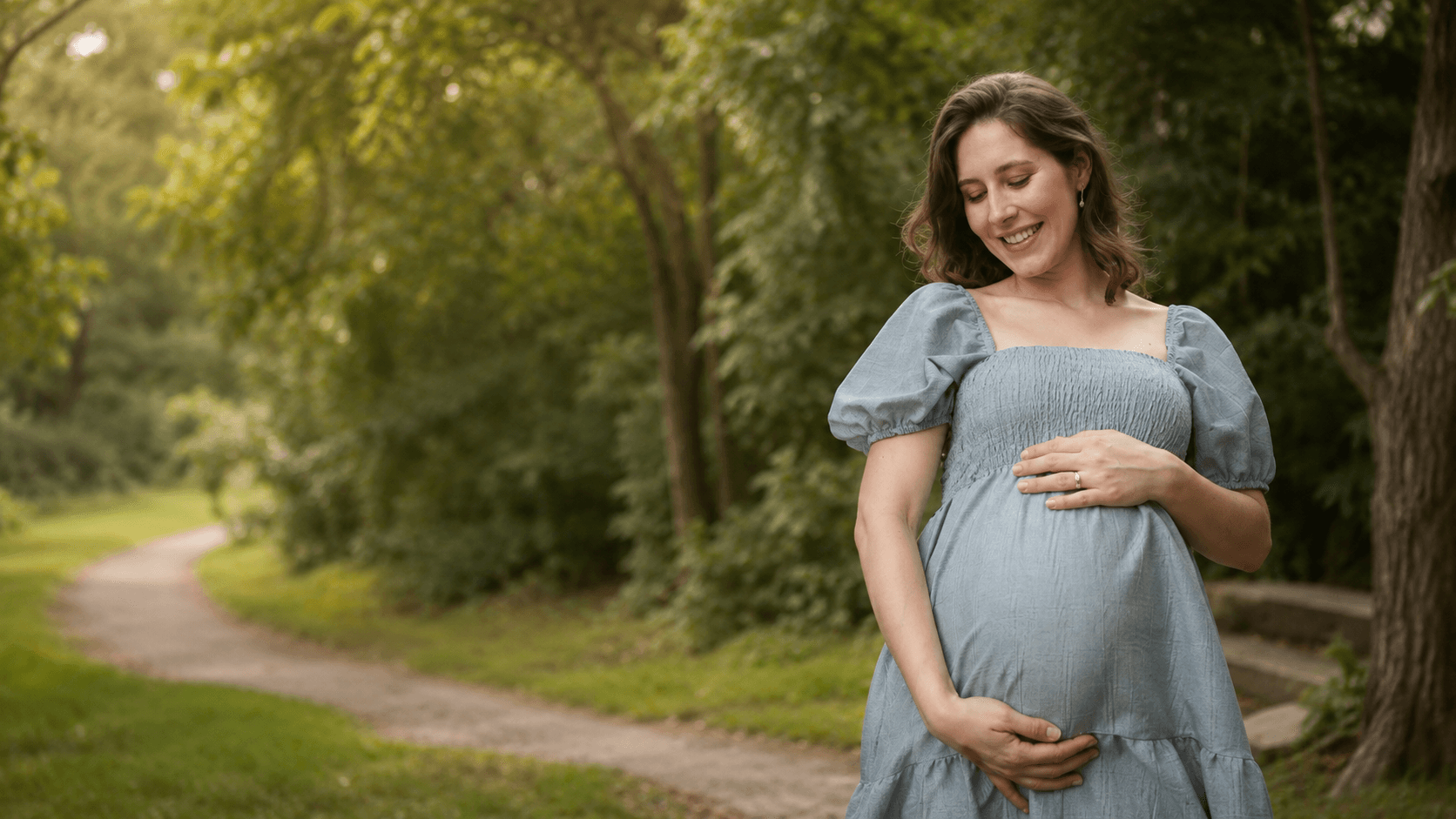 Gestante em um parque, com as mãos apoiadas na barriga